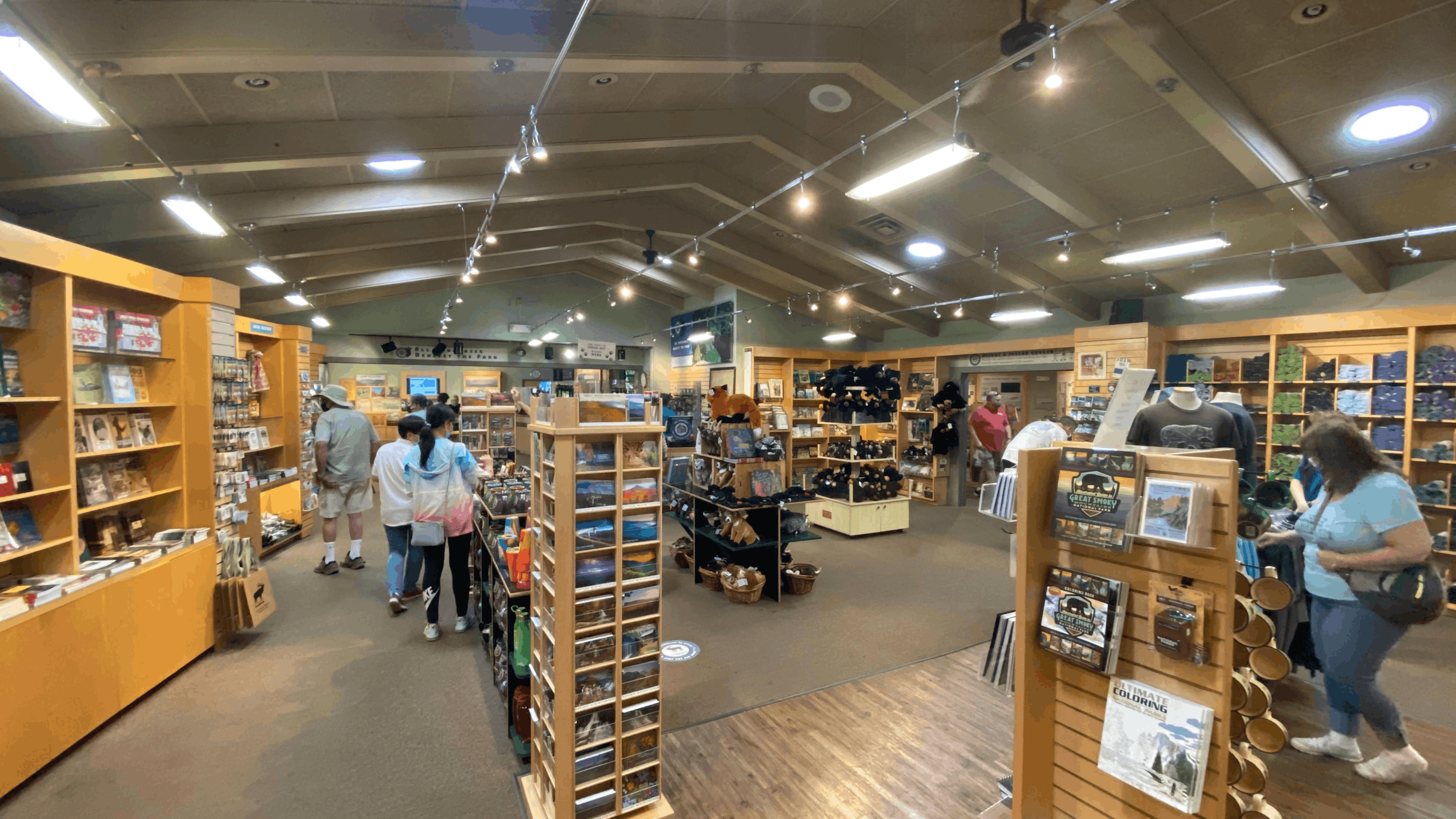 Visitors browsing a wildlife gift shop with souvenirs, books, and plush toys