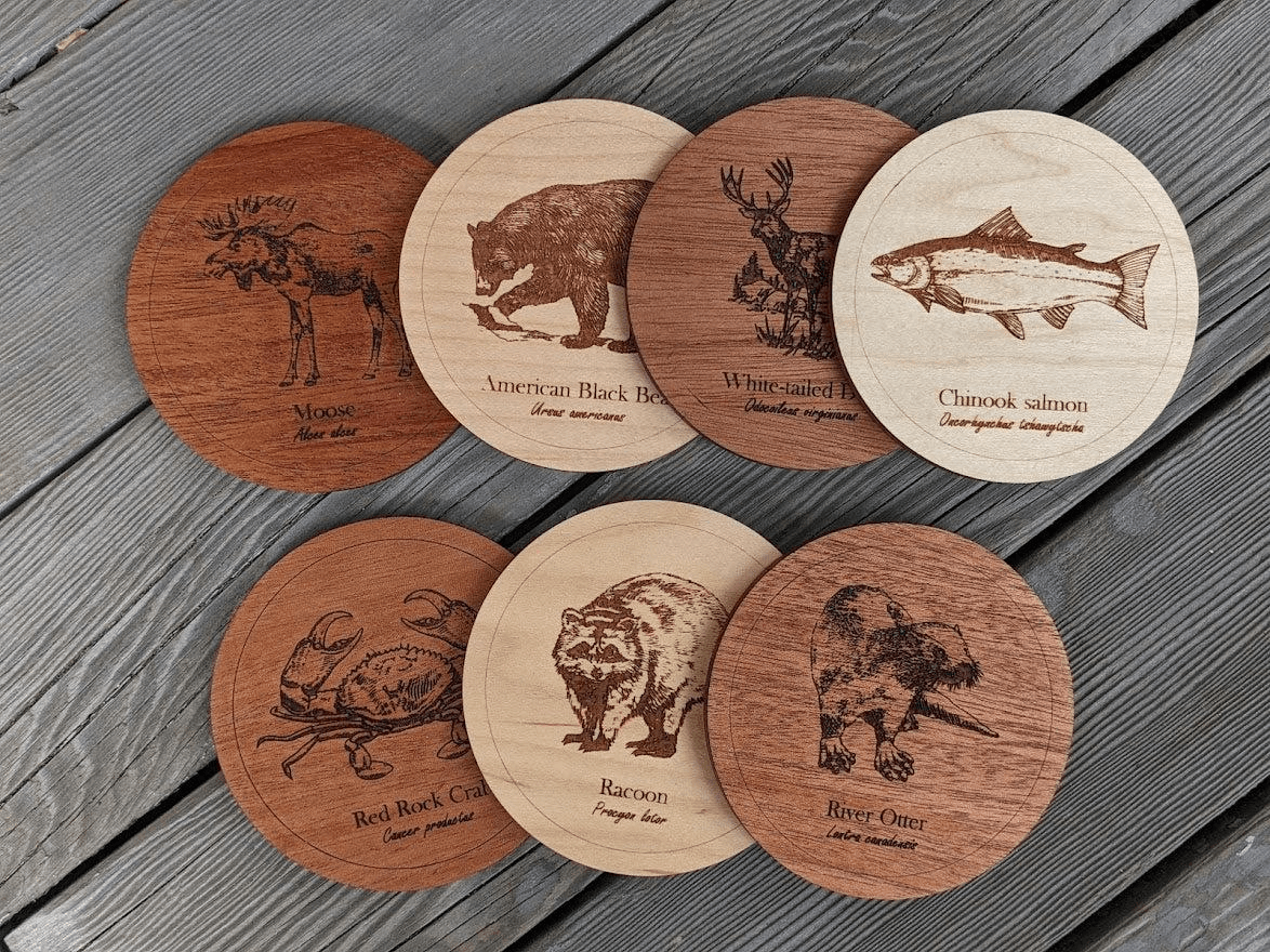 Wooden coasters engraved with wildlife designs including bear, moose, and salmon